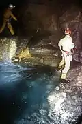 deux hommes debout passant au dessus d'une rivière souterraine