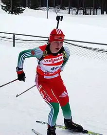 Biathlète féminine en train de skier, son fusil dans le dos.