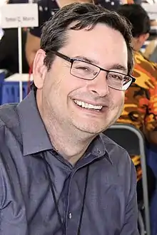 Un homme avec des lunettes souriant.