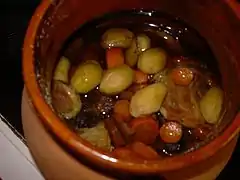 Dans un plat en terre cuite vernissée, les morceaux de viande et de légumes (carottes, pomme de terre) ont mijoté dans le vin rouge.