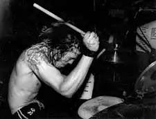 Dave Grohl jouant de la batterie torse nu pendant un concert en 1991.