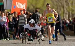 Un coureur donnant une tape amicale à un handisport au passage du ravitaillement du Trocadéro lors de l'édition 2014.