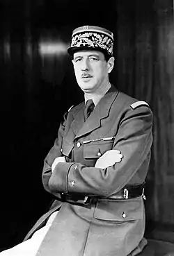 Photographie en noir et blanc de Charles de Gaulle, en uniforme de général de brigade. Son buste est tourné vers la gauche, et il a les bras croisés. Le cadrage masque ses jambes.