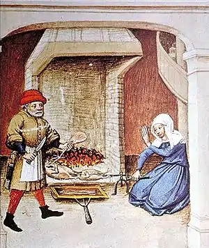 Homme au bonnet rouge un couteau à la main ; femme en bleu à genoux, tournant broche avec volaille devant une cheminée.