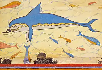 Fresque sur un fond jaune pâle montrant un dauphin avec le dos bleu, une ligne latérale ondulée jaune et le ventre blanc, entouré de poissons bleus et orange.