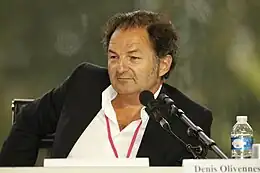 Photo d'Olivennes lors d'une conférence de presse en 2009, les cheveux en bataille, le front dégarni, situé devant deux micros et regardant sur sa droite.