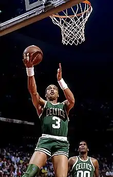 Un joueur sautant pour marquer un panier avec le numéro 3 des Celtics sous le regard du joueur portant le numéro 00