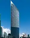 Ground-level view of a thin high-rises's curved, glass facade