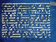 Un feuillet du Coran bleu de Kairouan avec la riche calligraphie d'or sur un fond bleu.