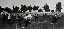 Photographie en noir et blanc d'une scène d'un match de football.