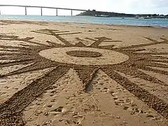 Dessin sur le sable de la plage représentant un flocon de neige.