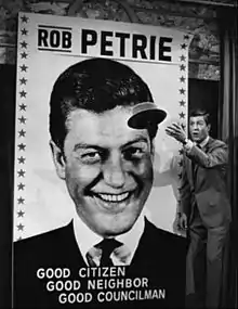 Photo d'un homme jetant son chapeau devant une affiche d'élection.