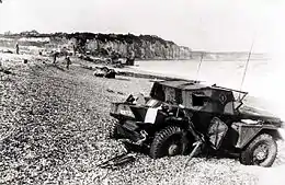 Photographie en noir et blanc de la carcasse d'un véhicule sur une plage
