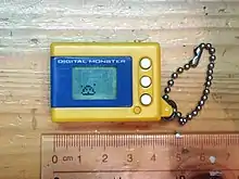 Petit gadget de couleurs jaune et bleu, posé sur une table en bois dont l'image est prise de dessus.