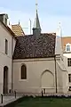 Vue latérale de la chapelle, de son toit en tuiles panachées et de son clocheton.