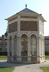 Petit bâtiment en pierre et brique avec arcades, surmonté d'un toit d'ardoises