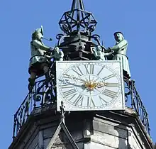 Vue en contre plongée, d'une horloge au sommet d'un campanile, avec deux statues de chaque coté