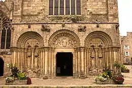 Photographie d'un bas de façade d'église avec trois arcades romanes