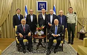 La cérémonie de remise des certificats d'appréciation aux employés du Mossad. Assis à droite se trouvent Reuven Rivlin, président de l'État d'Israël, et à gauche Benyamin Netanyahou, Premier ministre d'Israël. Les chefs du Mossad sont debout, de gauche à droite : Yossi Cohen, Shabtai Shavit,  Tamir Pardo, Nahum Admoni, Ephraim Halevy et Hasson Hasson - le secrétaire militaire du président (29 décembre 2015).