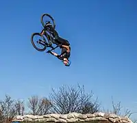 Un cycliste à plusieurs mètres en l'air et la tête en bas.