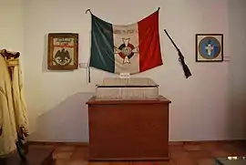 Drapeau d'une couleur sombre (bleu ?), blanc et rouge, avec inscrit "por dios y por la patra" et une croix au centre.