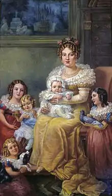 Tableau d'un portrait familial dans lequel Marie-Lépoldine est assise au centre, entourée d'enfants, tous très calmes, dans des costumes colorés.