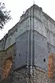 Photographie du coin d'un château fort depuis l'extérieur. Deux fenêtres sont visibles, le parement a disparu autour d'elles.