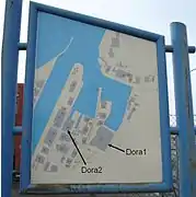 Panneau d'information montrant les bâtiments portuaires du fjord avec des flèches supplémentaires pour pointer les complexes de Dora.