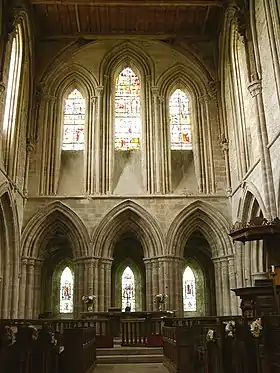 Photographie couleur du chevet d'une église, vu de l'intérieur, percé de deux niveau de verrières en lancettes