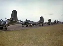 Photo couleur d'avions alignés sur un terrain plat et herbeux