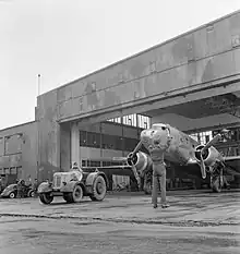 Avion bimoteur extrait d'un hangar par un tracteur