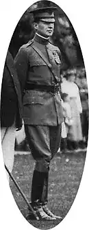 Homme portant un képi, une ceinture à bandoulière et des bottes de cavalier.