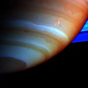 Vue de l'hémisphère sud de Saturne. Une spirale brillante est visible au-dessus d'une bande blanche.