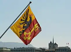 Le drapeau genevois suspendu au pont du Mont-Blanc avec la cathédrale Saint-Pierre en arrière plan.