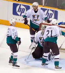 Photographie de quatre joueurs de hockey avec un maillot blanc.