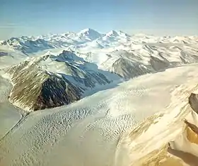 Vue aérienne de la confluence de deux glaciers dans un environnement montagneux couvert de neige.