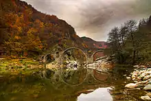 photographie couleurs : un pont à trois arches se reflétant dans une rivière ; couleurs d'automne