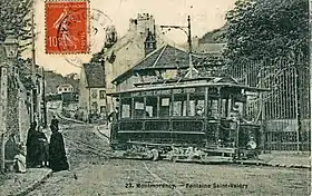 Carte postale noir et blanc : tramway devant une grille de propriété ; à bord le conducteur en uniforme.