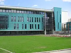 Photographie d'un bâtiment couleur turquoise, de la pelouse au premier-plan.