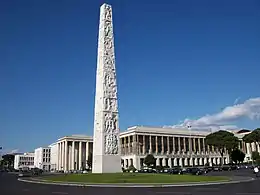 Photo d'un obélisque en marbre devant des grands bâtiments.