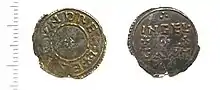 Photo des deux faces d'une pièce de monnaie, avec une petite croix entourée de texte à l'avers et deux lignes de texte séparées par une rangée de trois croix au revers