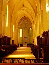 Photographie couleur du chœur d'une église gothique entouré de stalles.