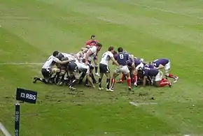 Photographie d'une mêlée dans un match de rugby à XV, entre l'équipe d'Écosse en maillots blancs et l'équipe de France en maillots bleus