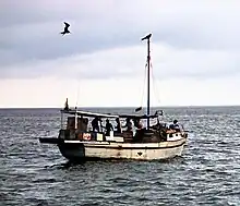 Un petit bateau de pêche artisanal en pleine mer avec des pêcheurs à son bord.