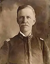Portrait noir et blanc d'un homme portant la moustache en tenue militaire.