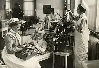 Infirmières, gâteaux et sapin de Noël autour d'un blessé pour le premier Noël de guerre, décembre 1914