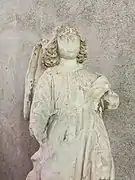 Vue sur une statue en pierre, le visage en partie mutilé.