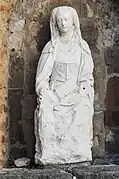 Statue en pierre de sainte Anne se tenant assise, un livre dans les mains.