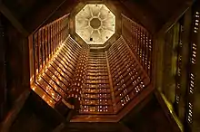 Vue en contre-plongée de la tour-lanterne baignée d'une lumière orangée et de son escalier hélicoïdal.