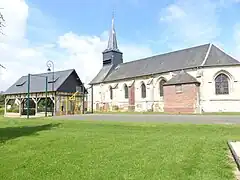 Façade sud de l'église, les aires de jeux et l'auvent abritant le broyeur de pommes à cidre.